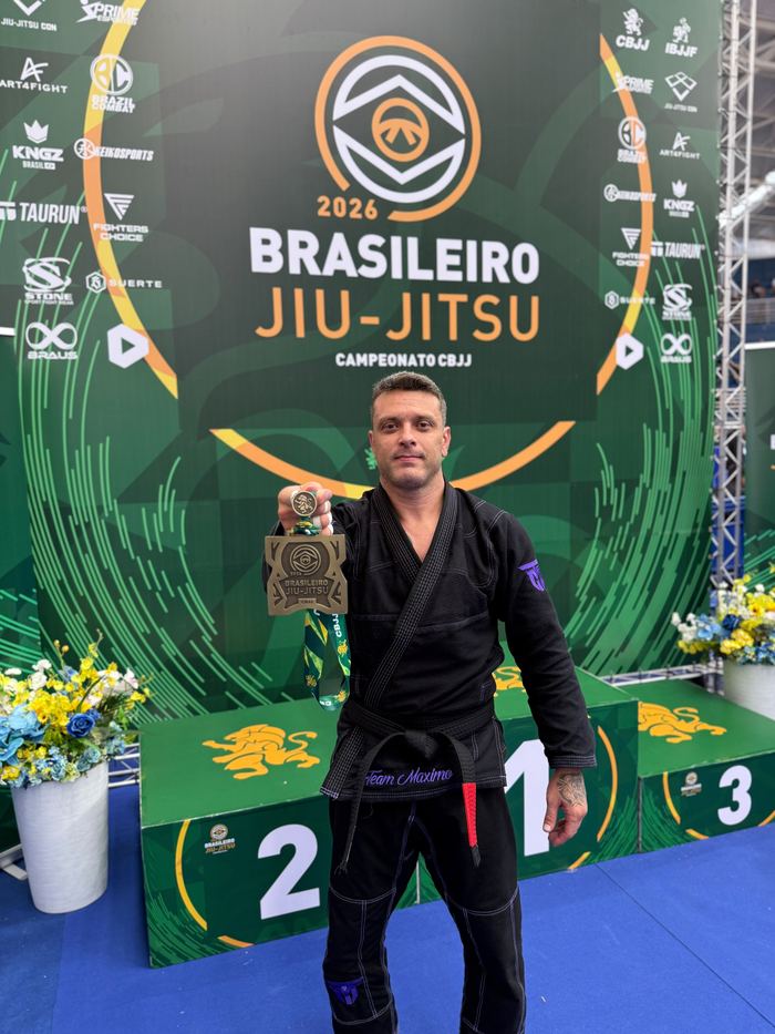Vinicius Máximo com medalha diante do painel do Campeonato Brasileiro de Jiu-Jitsu CBJJ 2026