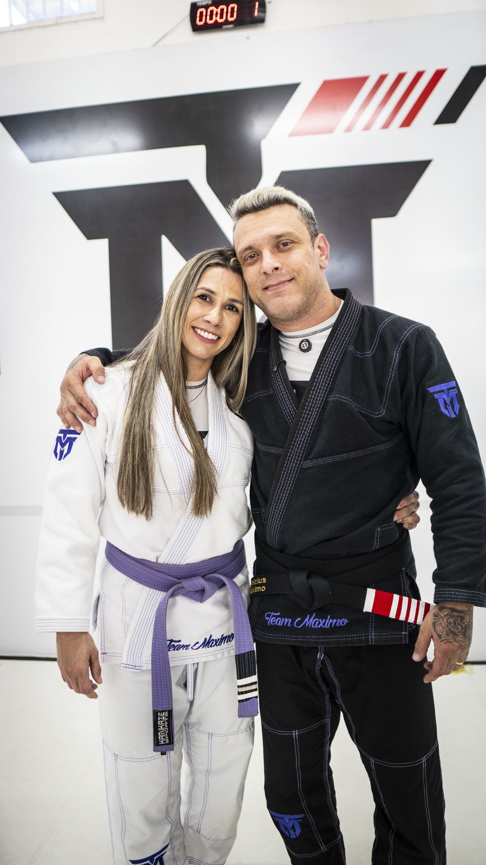Professor Vinicius Máximo ao lado da professora Aline, de kimono, na academia